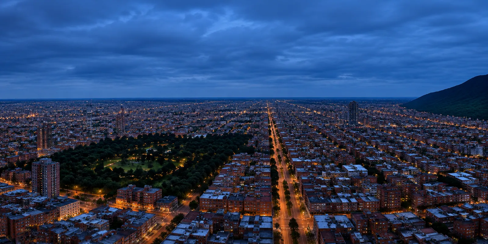 Bogotá al anochecer: la ciudad extendida sobre la sabana hasta el horizonte, con el cordón de cerros al costado oriental.